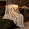 CloudHug blanket draped on a green velvet sofa by the fireplace